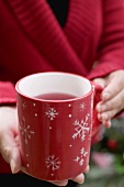 Woman holding mug of tea with snowflake motifs