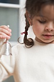 Small girl holding Christmas bell