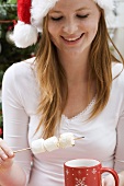 Woman in Father Christmas hat with marshmallows & cup of cocoa