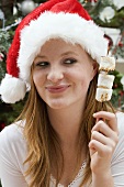 Woman in Father Christmas hat holding marshmallows on stick