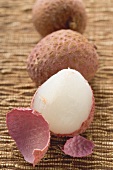 Three lychees in a row, one half-peeled