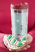 Woman holding candy cane biscuits and insulated beaker