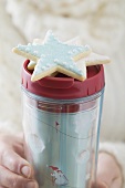 Woman holding star biscuit and insulated beaker