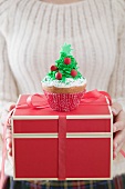 Frau hält Cupcake auf Weihnachtspaket