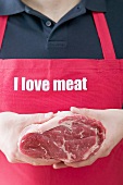 Man in apron holding fresh joint of beef