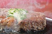 Steaming beef steak with herb butter on barbecue
