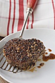 Peppered steak on spatula over plate
