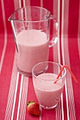 Strawberry milk in glass with straw, glass jug, strawberry
