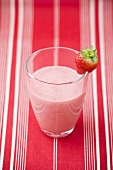Strawberry milk in glass with fresh strawberry on rim