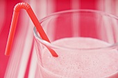 Strawberry milk in glass with straw (close-up)