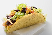 Taco filled with sweetcorn and beans on paper napkin