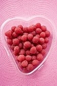 Raspberries in heart-shaped plastic container from above