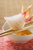 Dim sum on chopsticks over dip (Asia)