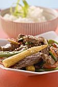 Rindfleisch mit Gemüse und Sesam, Reis im Hintergrund (Asien)