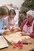 Grandmother showing grandchildren cut-out Christmas biscuit