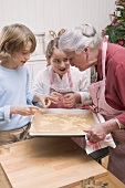 Grandmother showing grandchildren baking tray of Xmas biscuits