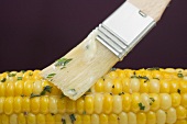 Brushing corn on the cob with herb butter