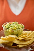 Frau hält Teller mit Guacamole und Nachos