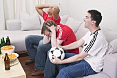 Football fans, disappointed and excited, watching TV