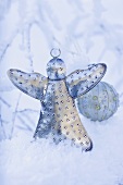 Silver angel and Christmas bauble in snow