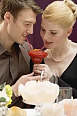 Romantic couple drinking Strawberry Daiquiri out of one glass