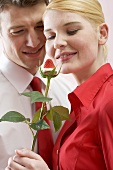 Romantic couple with chocolate-dipped strawberry on rose stalk
