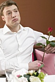 Lonely man with red rose in restaurant