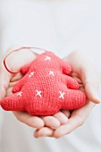 Hands holding knitted Christmas tree ornament