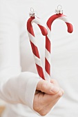 Hand holding Christmas tree ornaments (candy canes)