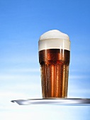 Glass of beer with head on tray