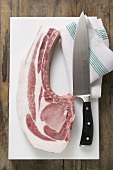 Fresh organic pork chop with knife on chopping board