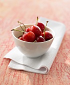 Several cherries in a bowl on a napkin