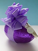 Chocolate Easter egg in purple foil with bow