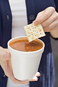 Woman holding tomato soup and cracker