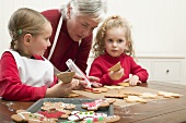 Grandmother & two granddaughters decorating Christmas biscuits