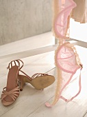 Pink bra on clothes stand, high-heeled shoes on floor