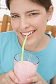Young woman drinking strawberry milk through a straw
