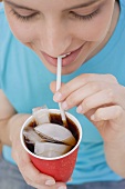 Young woman drinking cola through a straw