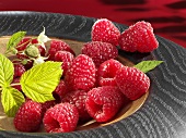 Raspberries with leaf in wooden bowl