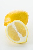 Half a lemon in front of a whole lemon