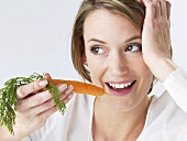 Woman about to bite into a carrot