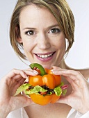 Frau hält Paprikaschote, mit Salat gefüllt
