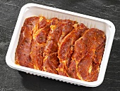 Marinated pork neck steaks in plastic container