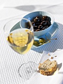 Oliven, Kapern, Brot und Glas Weißwein