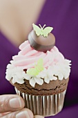 Woman holding a chocolate cupcake with butterflies