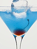 Blue Curaçao cocktail with cocktail cherry & ice cube