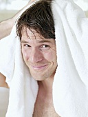 Mann trocknet seine Haare mit einem Handtuch