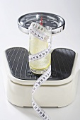 Glass of water with lime and tape measure on scales