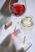 Glass of red wine, glass of white wine, fabric napkin, wine cork