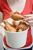 Woman holding deep-fried chicken drumsticks